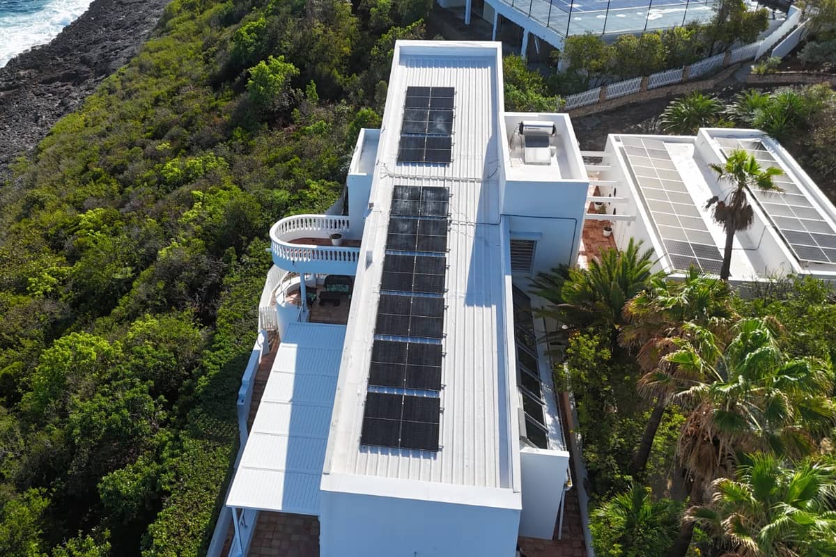 Aerial view of a clifftop property with a full rooftop solar array